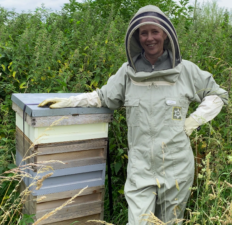Paula Carnell next to a beehive